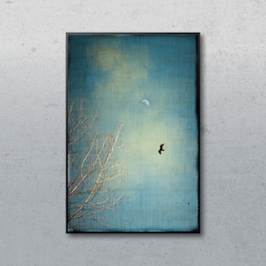 May include: A framed art print featuring a serene landscape. The artwork depicts a leafless tree on the left, a crescent moon, and a bird in flight against a blue and yellow sky. The print has a textured appearance.