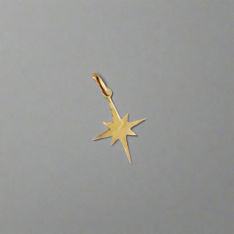 May include: A gold-colored starburst charm pendant with a loop for attaching to a necklace or bracelet.