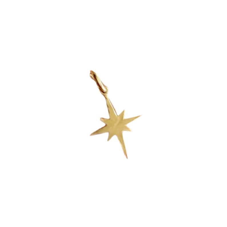 May include: A gold-toned star-shaped pendant charm with a loop for attaching to a necklace or bracelet.