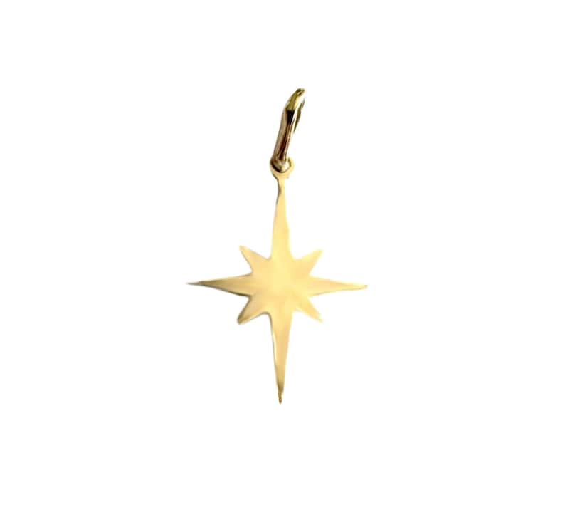 May include: A gold-colored star-shaped pendant with a pointed tip and eight points. The pendant has a loop at the top for attaching to a chain.
