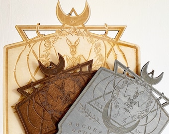 May include: Three wooden Ouija boards with a crescent moon design. The boards are in different shades of brown and gray. The boards have the letters of the alphabet, numbers, and the words "yes" and "no" printed on them.