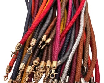 May include: A collection of braided leather cords with gold and silver clasps. The cords are in various colors, including red, orange, yellow, brown, blue, and gray.