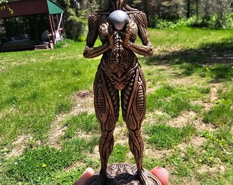 May include: A gold-colored, detailed, ornate statue of a woman holding a silver sphere. The statue is standing on a circular base with intricate designs.
