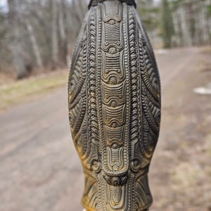 May include: A dark grey ceramic sculpture with intricate patterns and designs. The sculpture is shaped like a bird with a long, pointed beak and a rounded body.