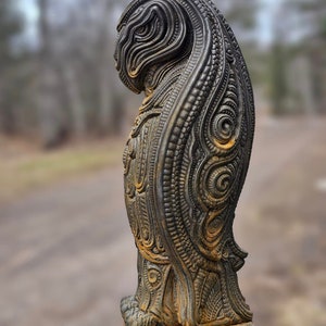 May include: A detailed, intricately carved, dark grey and brown statue of a mythical creature with a long, flowing mane. The statue is made of a textured material and has a base with a decorative design.