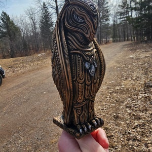 May include: A detailed, intricately carved owl sculpture with a gold and silver finish. The owl is standing on a square base with intricate carvings.