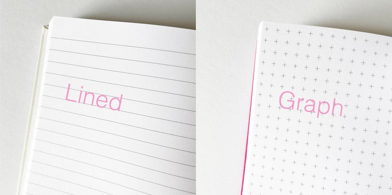 May include: Close-up of two open notebooks. The left notebook has lined pages and the word "Lined" printed in pink. The right notebook has graph paper and the word "Graph" printed in pink.