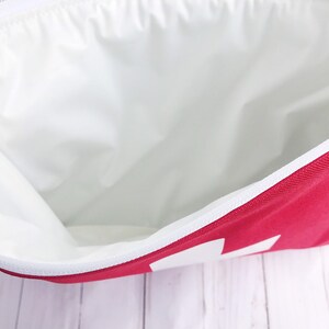 Puede incluir: Una bolsa roja con cremallera y forro blanco. La bolsa est&aacute; abierta y el forro es visible.