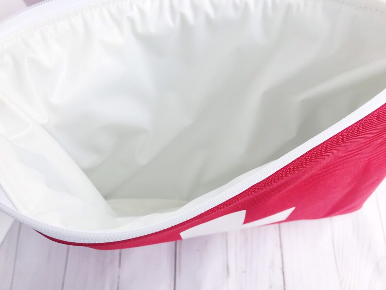 Puede incluir: Una bolsa roja con cremallera y forro blanco. La bolsa est&aacute; abierta y el forro es visible.