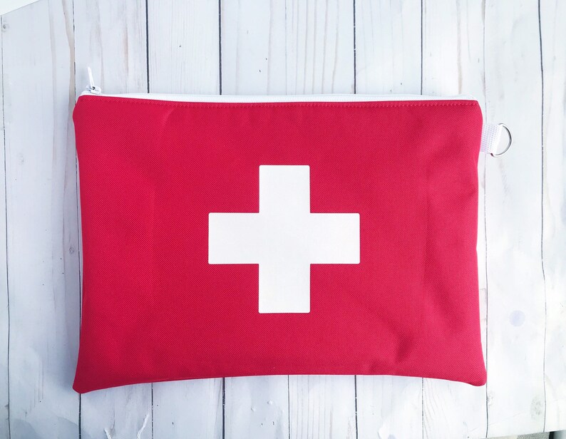 Puede incluir: Bolsa roja con cremallera con un signo m&aacute;s blanco en la parte delantera. La bolsa est&aacute; hecha de tela y tiene una cremallera.