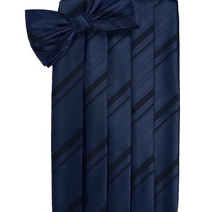 May include: A navy blue bow tie with black diagonal stripes. The bow tie is made of satin and has a pleated design.