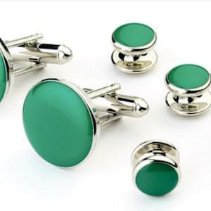 May include: A set of green and silver cufflinks and shirt studs. The cufflinks are round and have a green enamel finish. The shirt studs are also round and have a green enamel finish.