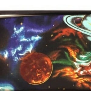 Puede incluir: Un conjunto en caja negra que contiene una pajarita y un pañuelo de bolsillo a juego, ambos con un diseño vibrante de temática espacial. La pajarita está preatada. El pañuelo y la pajarita muestran planetas, galaxias y nebulosas.