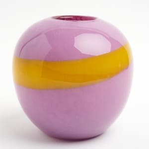 Puede incluir: Un jarrón esférico de vidrio con un acabado liso y brillante. El cuerpo del jarrón es principalmente de color violeta claro con una banda horizontal de color amarillo opaco que rodea el centro. La abertura en la parte superior es circular.