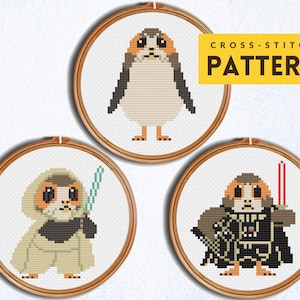 May include: Three cross-stitch patterns featuring characters from Star Wars. The patterns are in embroidery hoops and show a Porg in a Jedi robe, a Porg in a Darth Vader costume, and a Porg in a pilot's uniform.