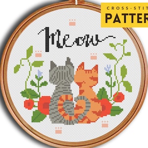 Puede incluir: Patrón de punto de cruz con dos gatos sentados espalda con espalda con un diseño floral y la palabra "Meow" encima.