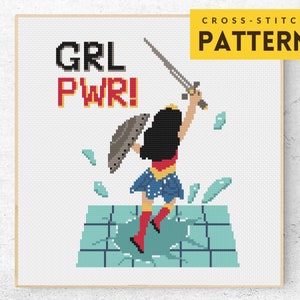 Könnte beinhalten: Kreuzstichmuster mit einer Comic-Superheldin mit Schwert und Schild, die auf einer zerbrochenen Oberfläche steht. Der Text "GRL PWR!" befindet sich über ihr.