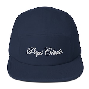 May include: A navy blue 5-panel cap with a white embroidered logo that says "Papi Chulo".