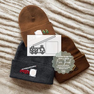 May include: Three beanies in brown and charcoal gray are displayed. One brown beanie has a small embroidered design. A charcoal gray beanie features a red and white embroidered fire truck. A paper with a fire truck design is placed on top. The text "Printable Design For Stick n' Stitch Fire Truck" is visible.