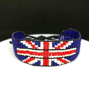 Pu&ograve; includere: Un braccialetto di perline con un designo a bandiera Union Jack in rosso, bianco e blu. Il braccialetto &egrave; realizzato con piccole perline colorate e ha una chiusura a cordoncino nero.