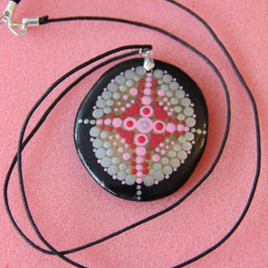 May include: A black stone pendant with a silver bail, painted with a mandala design in pink, red, and silver dots. The pendant is on a black cord.