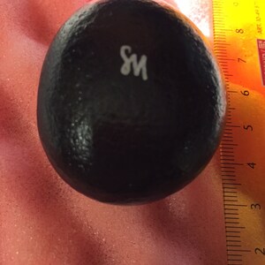 May include: A black, round, textured object with the letter "S" and "M" printed in white on the surface.