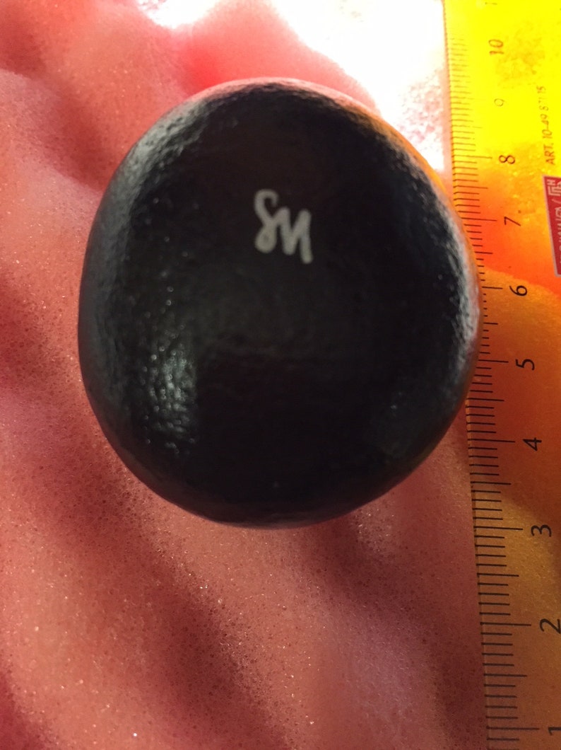 May include: A black, round, textured object with the letter "S" and "M" printed in white on the surface.
