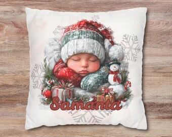 May include: A decorative Christmas pillow featuring a sleeping baby wearing a red and white hat and mittens. A snowman, gifts, and the name "Samanta" are also depicted. The pillow has a white background with snowflake accents.