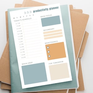 May include: A productivity planner with the title "3:3:3: productivity planner" on top of a stack of notebooks. The planner has sections for today's schedule, main focus, secondary tasks, maintenance, brain drop, and for tomorrow. The planner is light blue, with tan and beige accents.