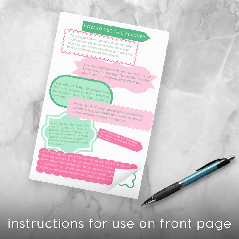 May include: A white planner page with instructions for use, featuring pink and green text boxes. A black and teal pen rests on the marble surface. The text reads "HOW TO USE THIS PLANNER" and "instructions for use on front page."