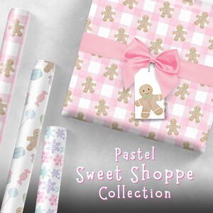 Peut inclure: Plusieurs rouleaux de papier d'emballage et une bo&icirc;te cadeau aux couleurs pastel. La bo&icirc;te cadeau est envelopp&eacute;e dans du papier vichy rose et attach&eacute;e avec un n&oelig;ud rose. Le papier pr&eacute;sente des bonhommes en pain d'&eacute;pices, des flocons de neige et des bonbons. Le texte "Pastel Sweet Shoppe Collection" est visible.