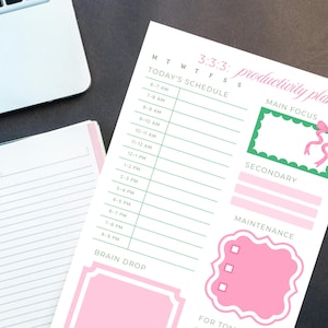 May include: A white productivity planner with a pink and green design. The planner includes sections for scheduling, main focus, secondary tasks, and maintenance. The text "3:3:3: productivity plan" is visible at the top.