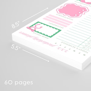 May include: A white productivity planner with pink and green accents. The planner is 8.5 inches by 5.5 inches and has 60 pages. Features include sections for main focus, secondary tasks, and a daily schedule.