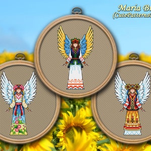 May include: Three cross-stitch angel designs in wooden embroidery hoops. Each angel wears a traditional Ukrainian outfit with detailed wings. The background features a sunflower field and blue sky. The text "Maria Brovko (CutePatternsByMaria)" is at the top.