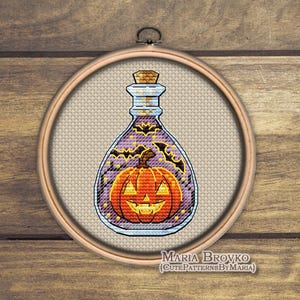 Könnte beinhalten: Ein Kreuzstich-Design einer Halloween-Zaubertrankflasche mit einem lächelnden Kürbis darin. Die Flasche ist lila mit schwarzen Fledermäusen und Sternen. Das Design ist in einem hölzernen Stickrahmen gerahmt. Der Text "MARIA BROVKO (CUTEPATTERNSBYMARIA)" steht unten.
