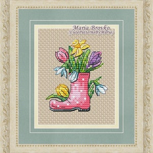 May include: A pink rubber boot with white polka dots filled with a bouquet of colorful flowers, including yellow daffodils, purple crocuses, and white snowdrops. The boot is sitting on a beige background. The text "Maria Brovko (CutePatternsByMaria)" is written above the boot.