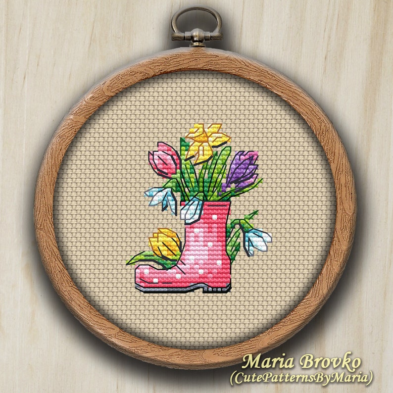 May include: A pink rubber boot with white polka dots filled with a bouquet of spring flowers, including yellow daffodils, purple crocuses, and white snowdrops.