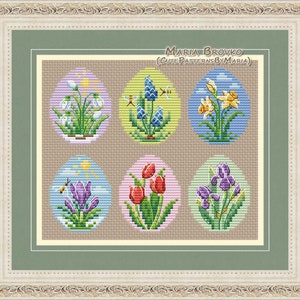 May include: Six colorful embroidered eggs with different spring flowers, including snowdrops, bluebells, daffodils, crocuses, tulips, and irises. The eggs are surrounded by a brown background and a white frame with ornate details. The text "Maria Brovko (CutePatternsByMaria)" is at the top of the image.
