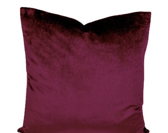 May include: A deep burgundy velvet pillow with a soft, plush texture. The pillow is square shaped and has a simple, elegant design.