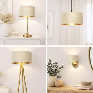 May include: A selection of gold-coloured lamps with beige fabric shades. The lamps include a table lamp, a pendant light, a floor lamp, and a wall sconce. The shades have a gold interior, and the bases are a matching gold colour. The lamps are designed for home decor.