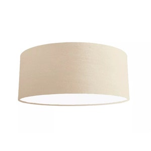 K&ouml;nnte beinhalten: Ein beigefarbener Lampenschirm aus Stoff mit wei&szlig;em Innenleben. Der Lampenschirm ist rund und hat eine glatte Oberfl&auml;che.