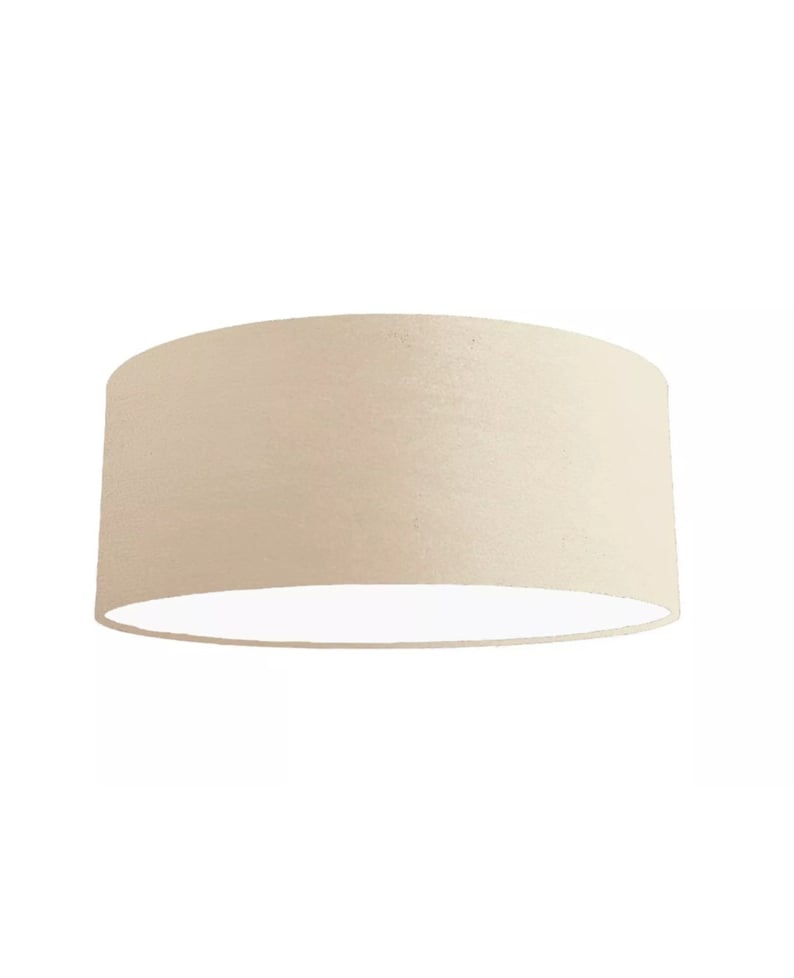 K&ouml;nnte beinhalten: Ein beigefarbener Lampenschirm aus Stoff mit wei&szlig;em Innenleben. Der Lampenschirm ist rund und hat eine glatte Oberfl&auml;che.