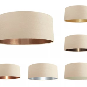 K&ouml;nnte beinhalten: Satz mit sechs cremefarbenen Lampenschirmen mit verschiedenen farbigen Metallic-Innenfl&auml;chen. Die Schirme sind rund und haben eine glatte Textur. Die Metallic-Innenfl&auml;chen sind gold, kupfer und silber.