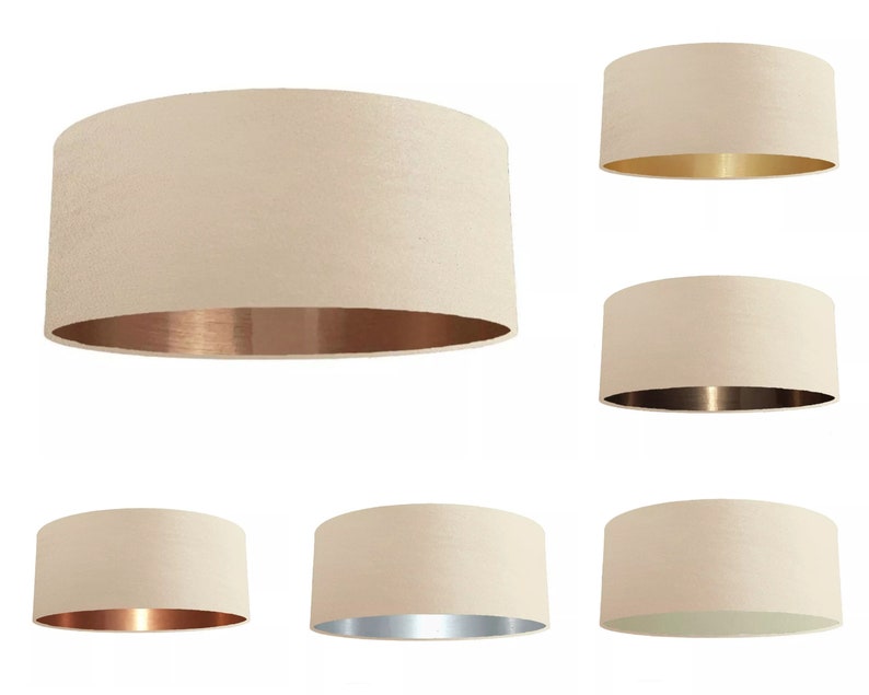 K&ouml;nnte beinhalten: Satz mit sechs cremefarbenen Lampenschirmen mit verschiedenen farbigen Metallic-Innenfl&auml;chen. Die Schirme sind rund und haben eine glatte Textur. Die Metallic-Innenfl&auml;chen sind gold, kupfer und silber.