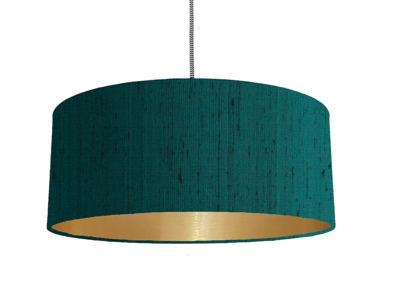 May include: A teal blue drum lampshade with a gold inner lining. The lampshade is made of a textured fabric.