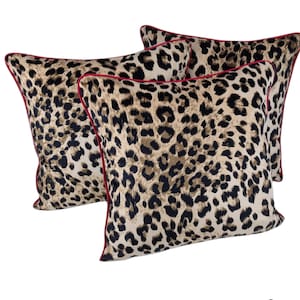 May include: Two brown and black leopard print throw pillows with red piping.