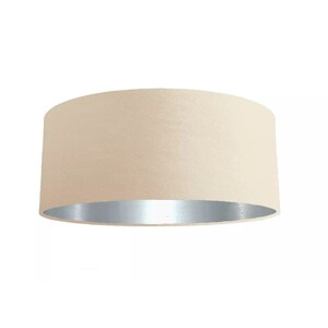 K&ouml;nnte beinhalten: Ein beiger Trompetenlampenschirm mit silberner Innenverkleidung. Der Lampenschirm ist aus Stoff und hat eine glatte, gleichm&auml;&szlig;ige Textur.
