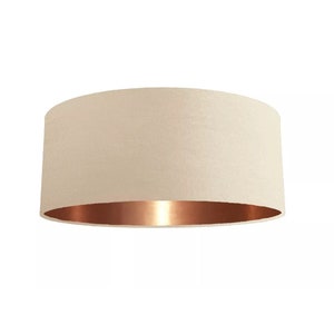 K&ouml;nnte beinhalten: Ein cremefarbener Lampenschirm mit einem kupferfarbenen unteren Rand.