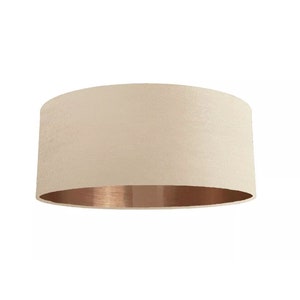 K&ouml;nnte beinhalten: Ein beigefarbener Lampenschirm mit einem kupferfarbenen unteren Rand.
