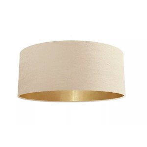 K&ouml;nnte beinhalten: Ein cremefarbener Lampenschirm mit goldfarbenem Metallic-Besatz. Der Lampenschirm ist aus Stoff und hat eine glatte, gleichm&auml;&szlig;ige Textur.